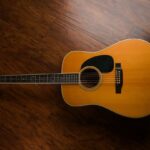 Vintage akoestische gitaar met warme houtkleur op een donkere houten vloer