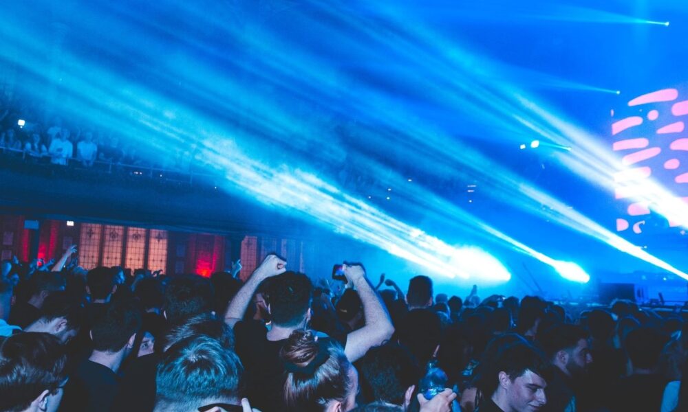 Dansend publiek onder blauwe lichtstralen tijdens een nachtelijk concert