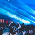 Dansend publiek onder blauwe lichtstralen tijdens een nachtelijk concert